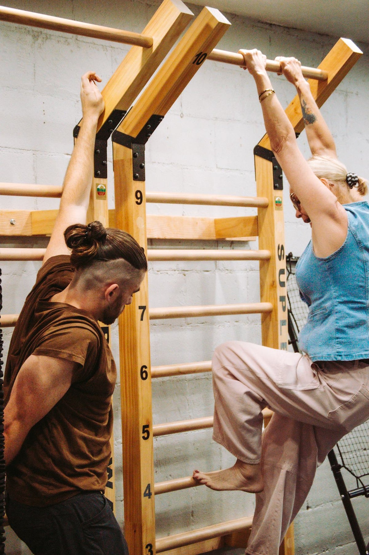 Alex coaching a guest on the wall bars